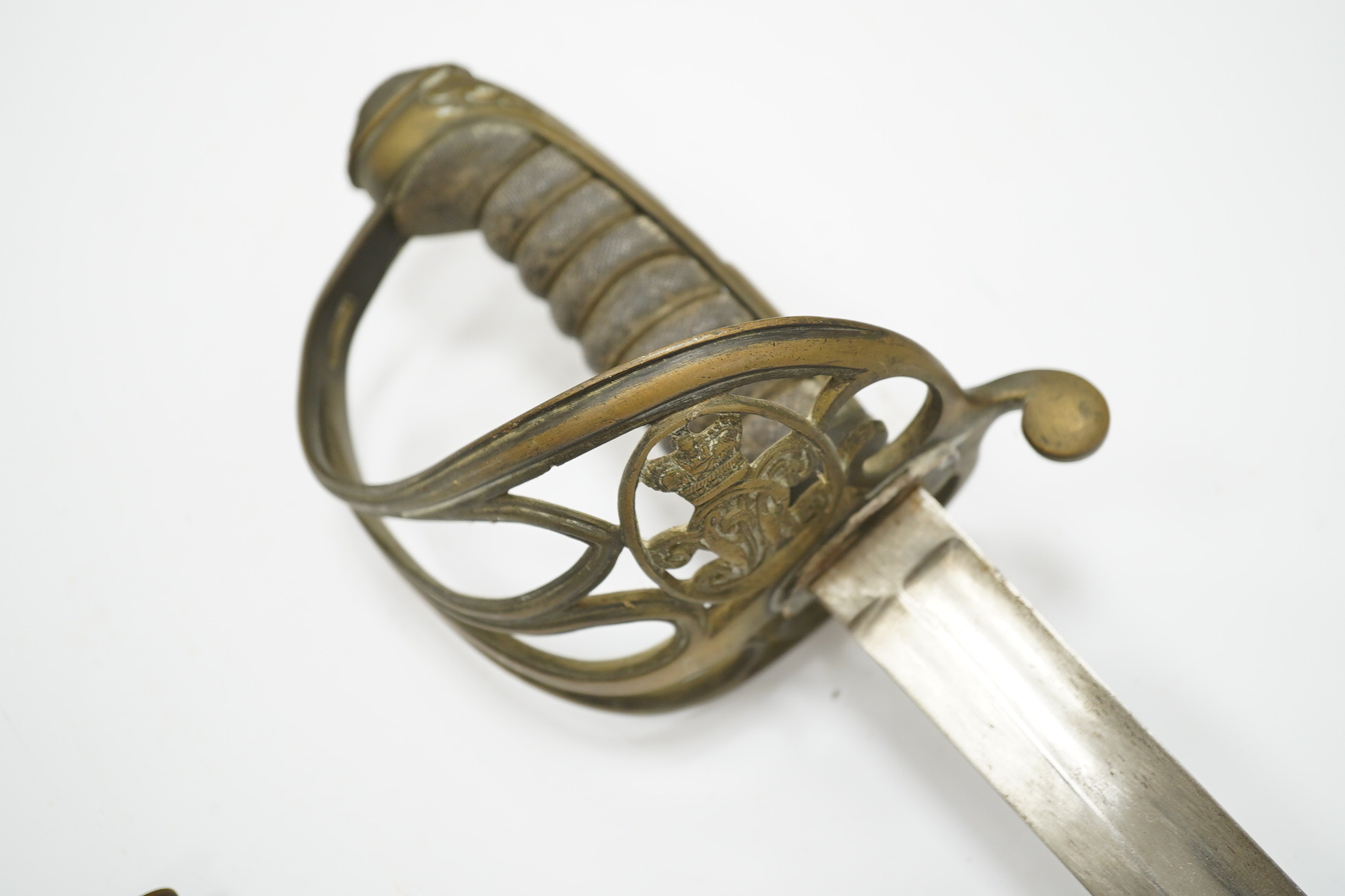 An 1845 pattern infantry officer’s sword, with plain slightly curved blade, regulation solid brass guard, and wire bound fish covered grip, in its brass mounted leather scabbard. Condition - poor to fair, blade cleaned b